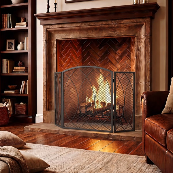 Dreiteiliges Funkenschutzgitter vor einem Kamin mit brennendem Feuer in einem gemütlichen Wohnzimmer mit Bücherregal.