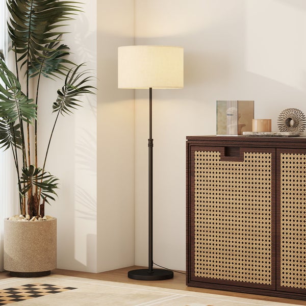 Stehleuchte mit Textilschirm neben einer Zimmerpflanze und einem Sideboard mit Wiener Geflecht im Wohnzimmer