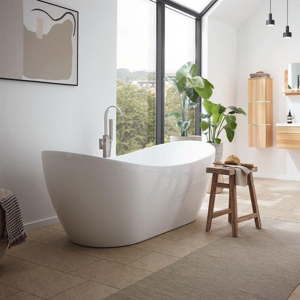 Freistehende Badewanne in einem hellen, modernen Badezimmer mit bodentiefem Fenster, Holzmöbeln und einem rustikalen Holzhocker als Ablage.