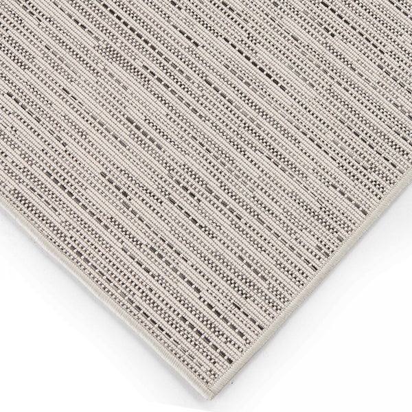 Eckdetail eines hellen Flachgewebe-Teppichs mit feiner Linienstruktur und geketteltem Rand.
