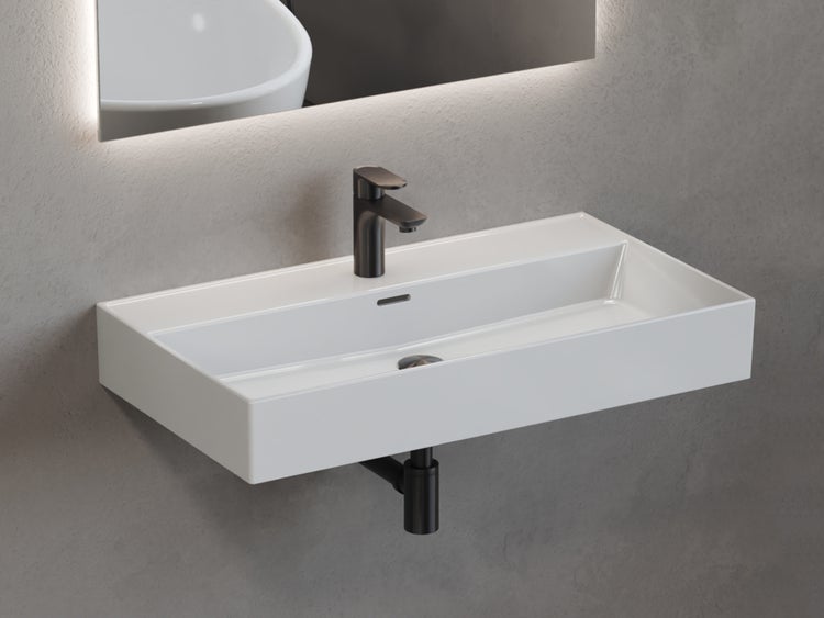 Wandhängendes rechteckiges Waschbecken aus weißer Keramik mit schwarzer Armatur und schwarzem Siphon unter einem beleuchteten Spiegel.