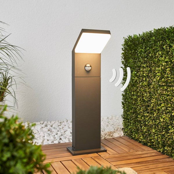 Moderne LED-Wegleuchte in Anthrazit mit integriertem Bewegungsmelder auf einer Holzterrasse im Garten.