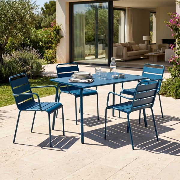 Modernes Garten-Set: blauer rechteckiger Metalltisch und vier Metallstühle auf einer Steinterrasse im Außenbereich.