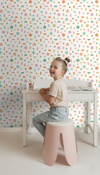 Vliestapete im Kinderzimmer mit geometrischem Muster aus Kreisen und Halbkreisen hinter einem Kinderschreibtisch in heller und organisierter Umgebung.