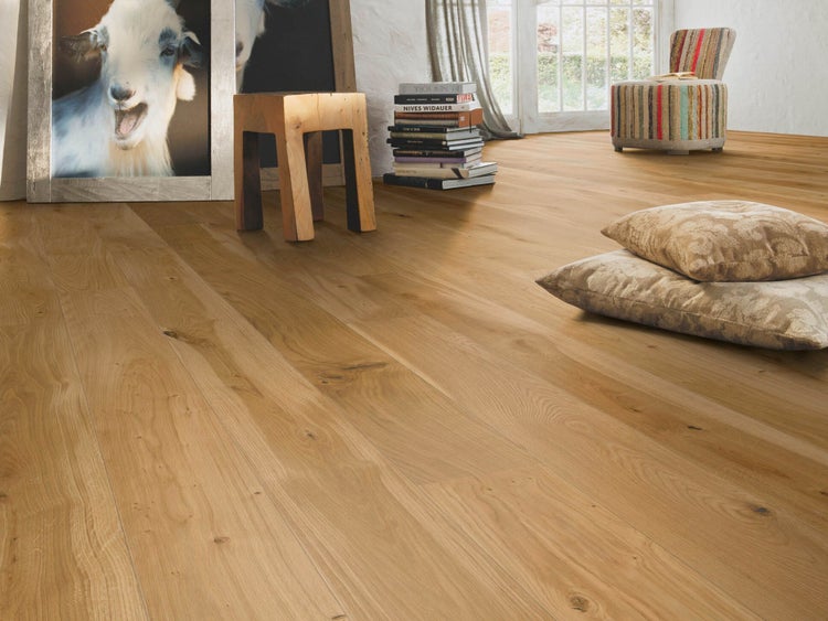 Parkett Landhausdiele aus Eiche in hellem Wohnzimmer mit Holzhocker und Dekorationskissen.