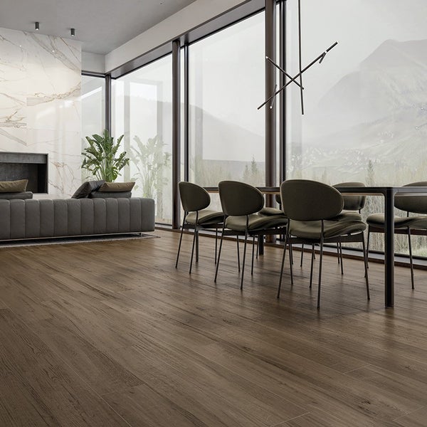 Geräumiger Wohnbereich mit dunklem Holzoptikboden, moderner Sitzgruppe, großem Esstisch und bodentiefen Panoramafenstern mit Bergblick.