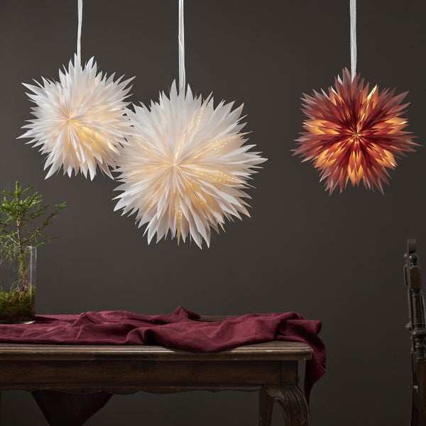 Dekorative Szene mit Papiersternen als Hängelampen über einem Tisch mit Dekoration