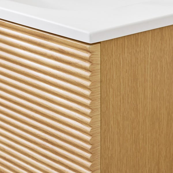 Detailaufnahme eines Waschtischunterschranks mit geriffeltem Holzdesign und weißer Oberfläche