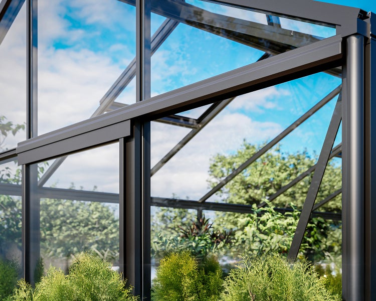 Detailansicht eines Gewächshauses mit anthrazitfarbenen Aluminiumprofilen und Glaspaneelen, im Inneren wachsen grüne Pflanzen.