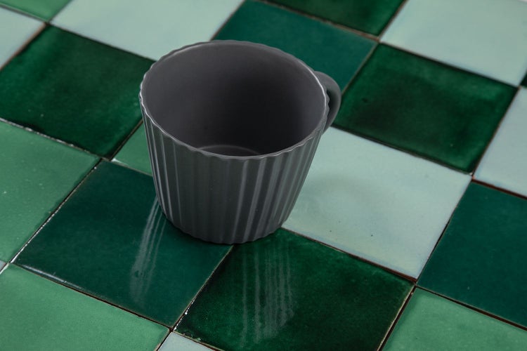 Gerippte Tasse auf quadratischen Fliesen