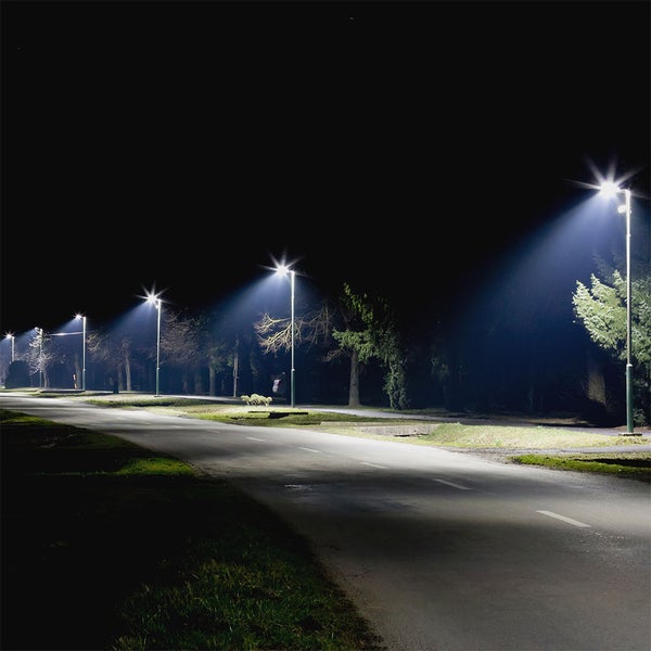 Reihe moderner Straßenlaternen beleuchtet einen asphaltierten Weg bei Nacht mit hellem, klarem Licht.