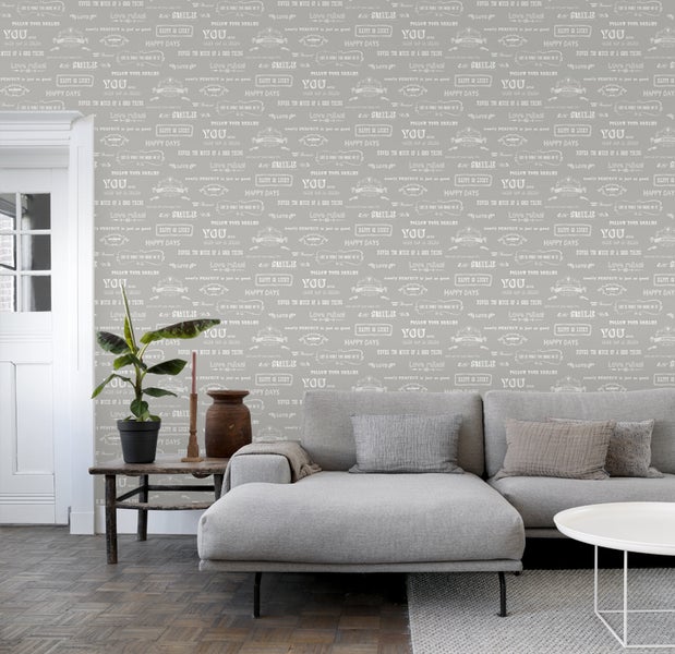 Wohnzimmer mit grauer Tapete mit Schriftzug, Sofa, Tisch und Zimmerpflanze