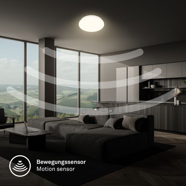 Runde Deckenleuchte mit Bewegungssensor in einem modernen Wohnzimmer mit offener Küche und großen Fenstern.