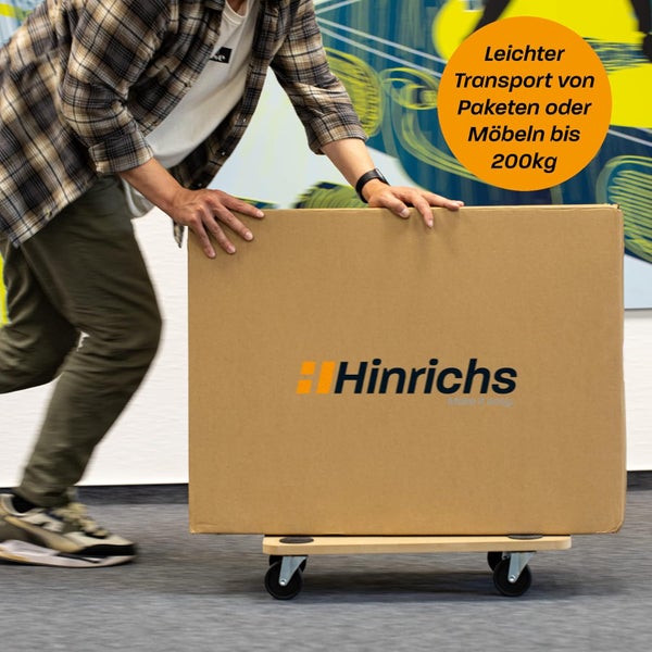Person transportiert Paket auf einem Möbelroller mit der Aufschrift Hinrichs.