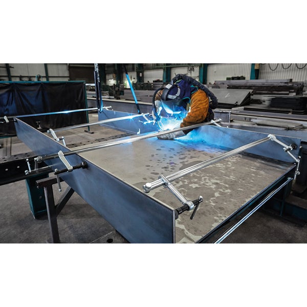 Schweißer bei der Arbeit an einer Metallkonstruktion, befestigt mit Schnellspannern.