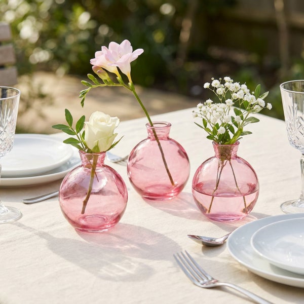 Set aus drei bauchigen Glasvasen in runder Form auf einem gedeckten Tisch mit Blumen dekoriert.