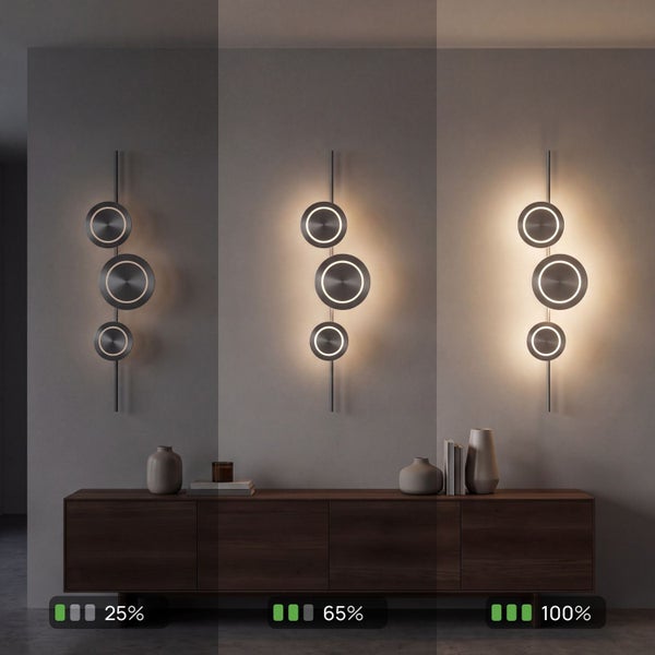 Moderne LED-Wandleuchte mit drei Metallscheiben über einem Sideboard, dimmbar in drei Stufen: 25 Prozent, 65 Prozent und 100 Prozent.