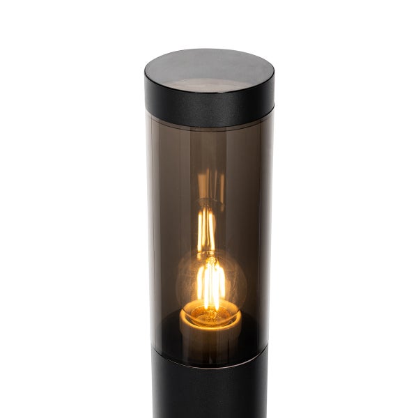 Zylindrische Außenstandleuchte aus schwarzem Metall mit getöntem Schirm und leuchtendem LED-Filament-Leuchtmittel.