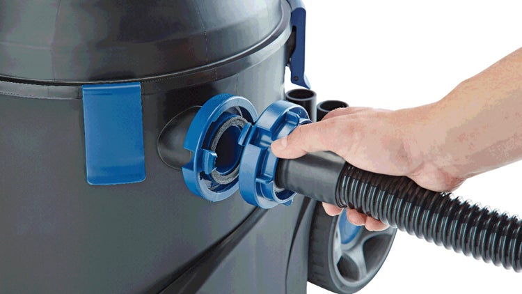 Hand verbindet Saugschlauch mit dem Anschluss eines Nass-Trockensaugers.