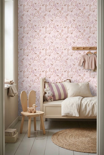 Vliestapete mit Waldtier-Motiven wie Hirschen und Hasen in einem hellen Kinderzimmer mit Holzbett, Hasen-Stuhl und geflochtenem Rundteppich.