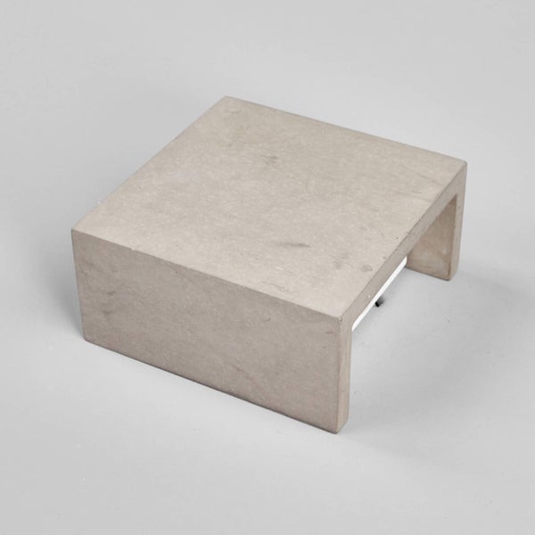 Quadratische LED-Außenleuchte aus grauem Beton in U-Form.