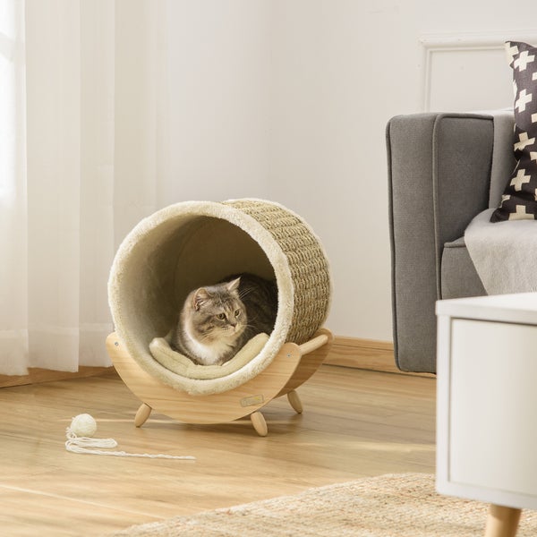 Katze in einem runden Katzenbett mit Holzrahmen und Spielzeug im Wohnzimmer