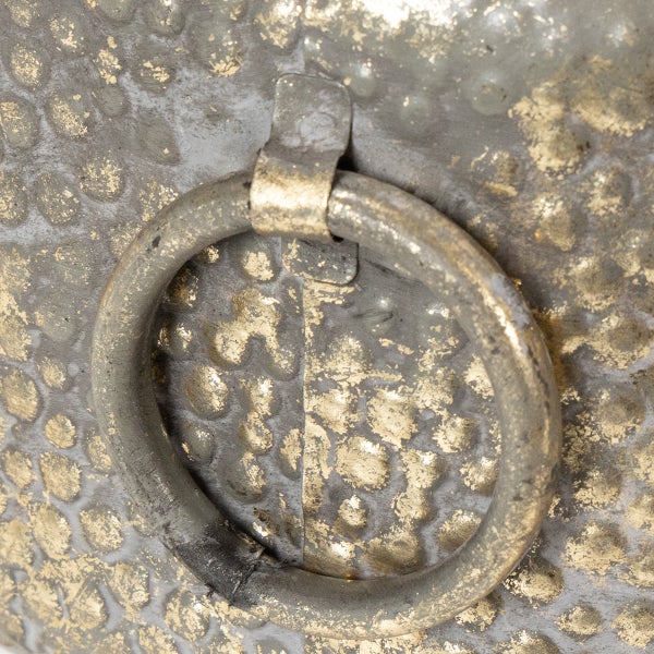 Detailansicht eines Metallringgriffs auf einer gehämmerten Oberfläche im Antik-Stil.
