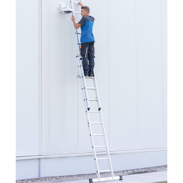 Ein Mann steht auf einer Aluminium Mehrzweckleiter und befestigt eine Überwachungskamera an einer Wand.