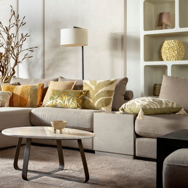 Wohnzimmer mit Sofa, Kissen, Couchtisch und Regal