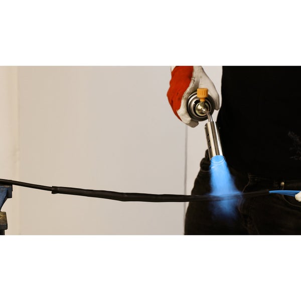 Mann schrumpft Kabelschutzschlauch mit Heißluftpistole, Schraubstock, Tauchpumpe und Kabelbinder auf Werkbank.