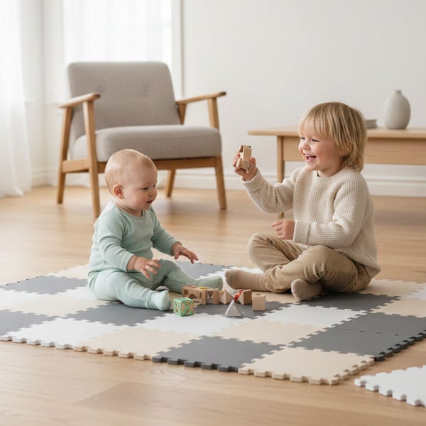 Zwei Kinder spielen auf einer Puzzlematte aus Schaumstoff in einem hellen, wohnlich eingerichteten Zimmer.