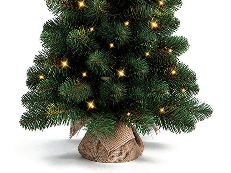 Künstlicher Weihnachtsbaum mit LED Lichterkette und Jutesack als Ständer.