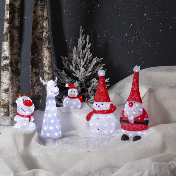 Dekorationsszene mit beleuchteten Weihnachtsfiguren und Bäumen auf einer verschneiten Oberfläche