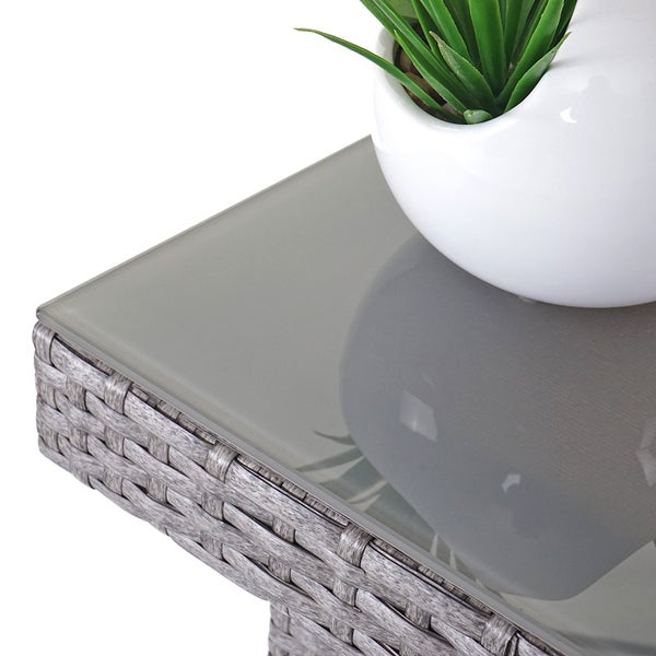 Detailansicht der Ecke eines Gartentisches aus Polyrattan-Geflecht mit Glasplatte und Topfpflanze.