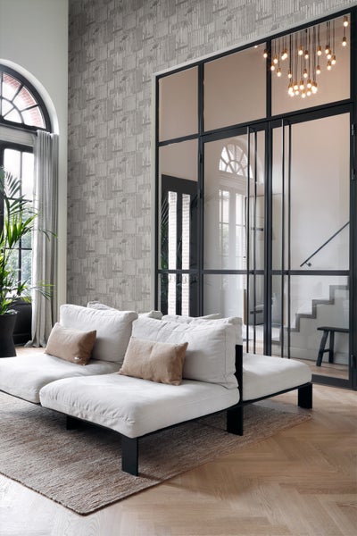 Heller Wohnraum mit gemusterter Tapete, Sofa, Teppich und Glastüren