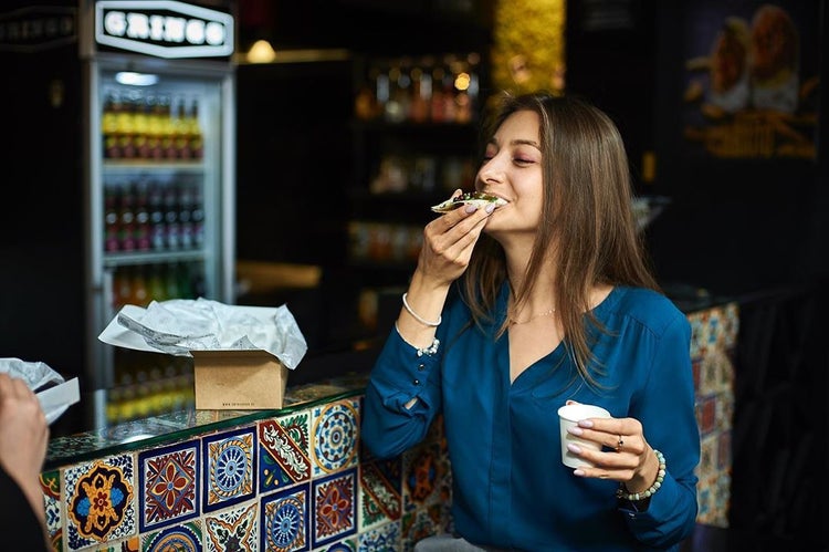 Eine Frau isst einen Snack in einem Restaurant.
