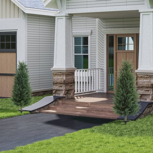 Heller Eingangsbereich eines modernen Hauses mit grauer Fassade, Naturstein-Säulen, Holzstufen und zwei kleinen Tannen auf dem Rasen.