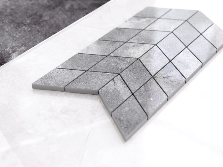 Mosaikfliese in Rautenform mit Steinoptik in Grau.