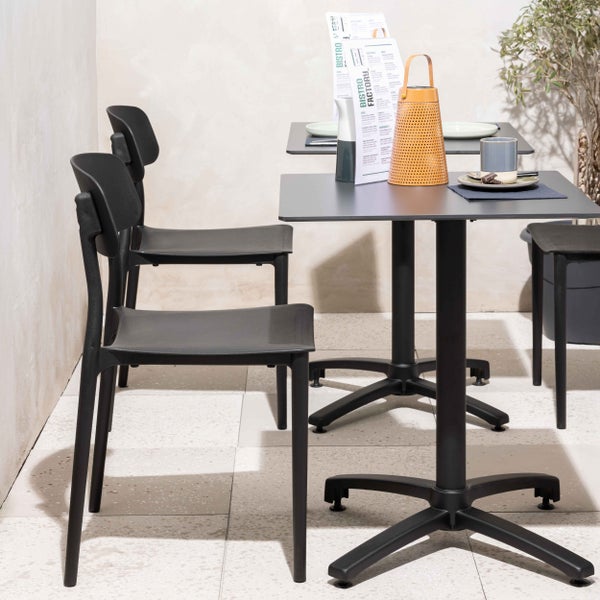 Modernes Bistro-Set mit schwarzen Kunststoffstühlen und quadratischen Bistrotischen in einem hellen, organisierten Gastronomiebereich.