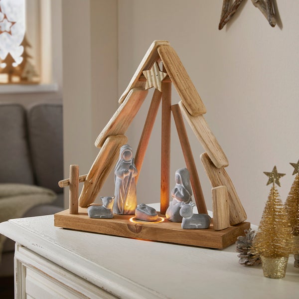 Krippenszene mit Holzstall und Figuren auf einem Tisch