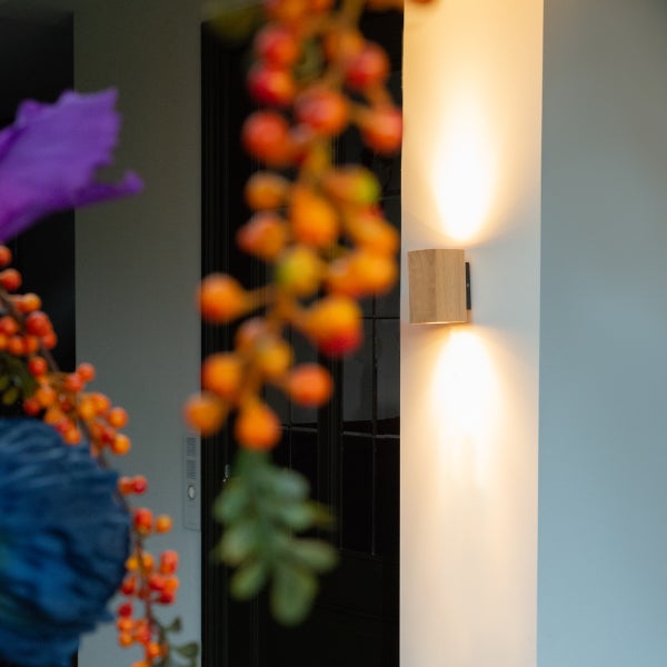 Moderne Wandleuchte aus Holz mit Up-Down-Lichteffekt an einer Hauswand montiert
