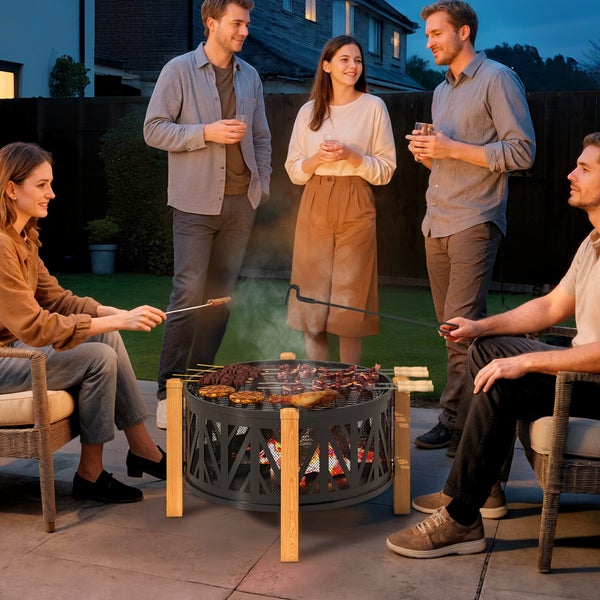 Gruppe von Freunden grillt am Abend im Garten mit einer Feuerschale.