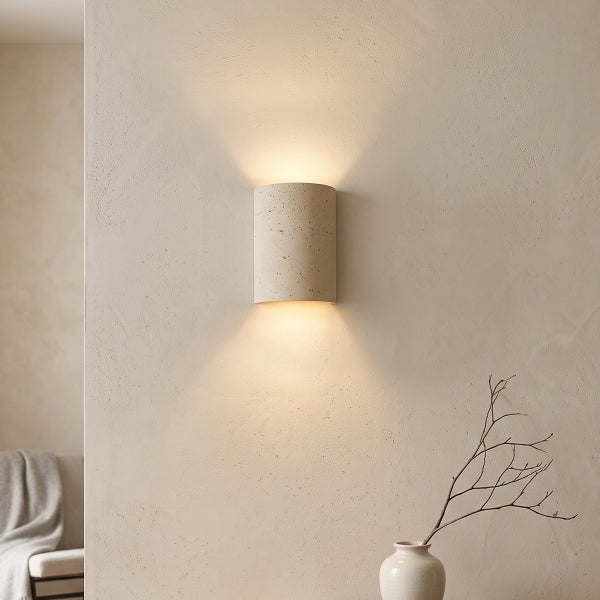 Zylindrische Wandleuchte aus Beton mit Up und Down Lichteffekt an einer strukturierten Wand in einem Wohnraum.
