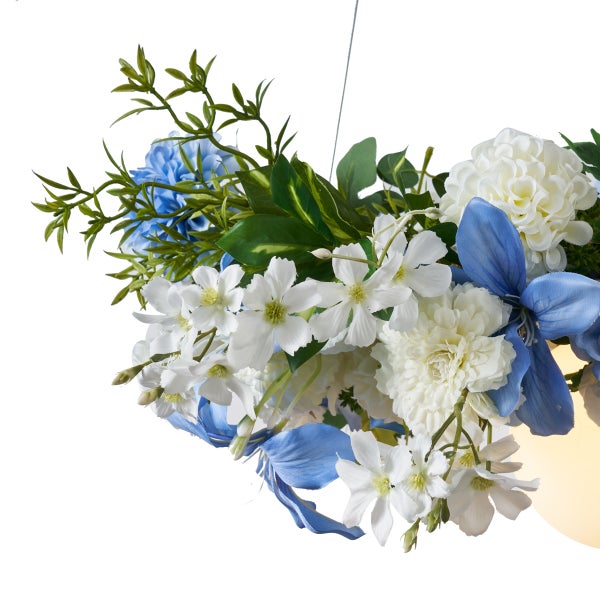 Künstliches Blumengesteck mit blauen und weißen Blüten sowie grünem Blattwerk