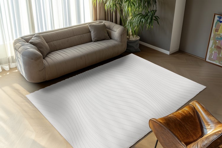 Ein moderner, rechteckiger Teppich mit Wellenmuster liegt in einem eleganten Wohnzimmer vor einem Sofa und einem Sessel auf Parkettboden.