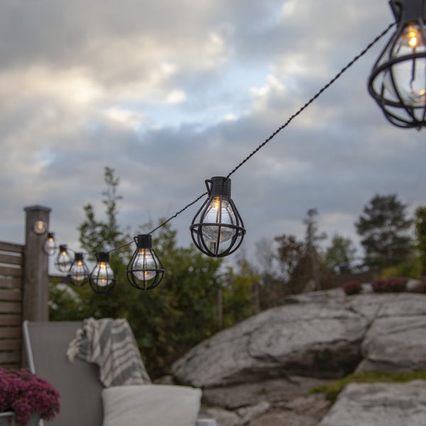 Beleuchtete LED-Lichterschläuche umwickeln weiße Säulen auf einer Veranda.