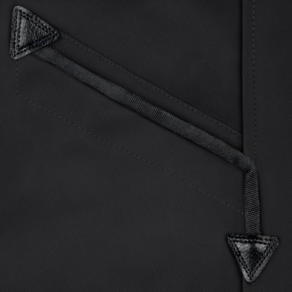 Nahaufnahme eines Taschendetails mit dreieckigen Lederverstärkungen und einem Band auf schwarzem, robustem Arbeitskleidungsgewebe.