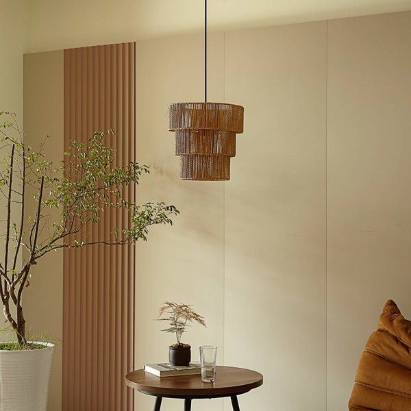Dreistöckige Pendelleuchte aus Naturfaser in einem hellen Wohnzimmer mit Beistelltisch und Zimmerpflanzen.