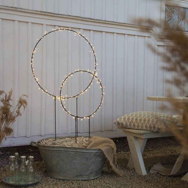 Dekorative Gartenbeleuchtung mit zwei beleuchteten Kreisen in einem Zinktopf.