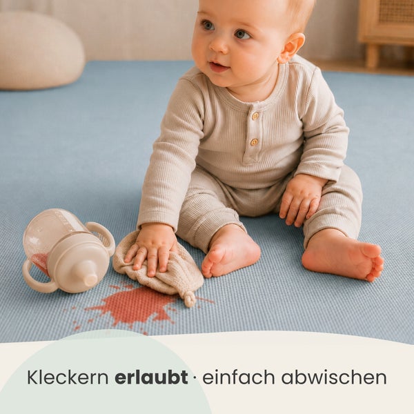 Kleinkind sitzt auf einer abwischbaren Spielmatte und wischt einen Fleck auf, Werbeslogan Kleckern erlaubt einfach abwischen.